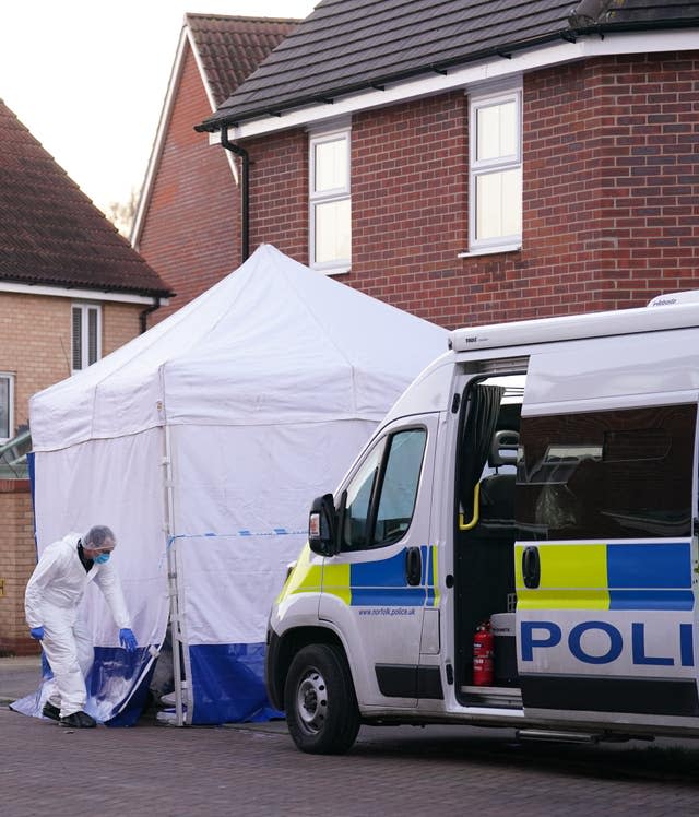 A forensic investigator outside a house in Costessey near Norwich after four people were found dead inside the property.