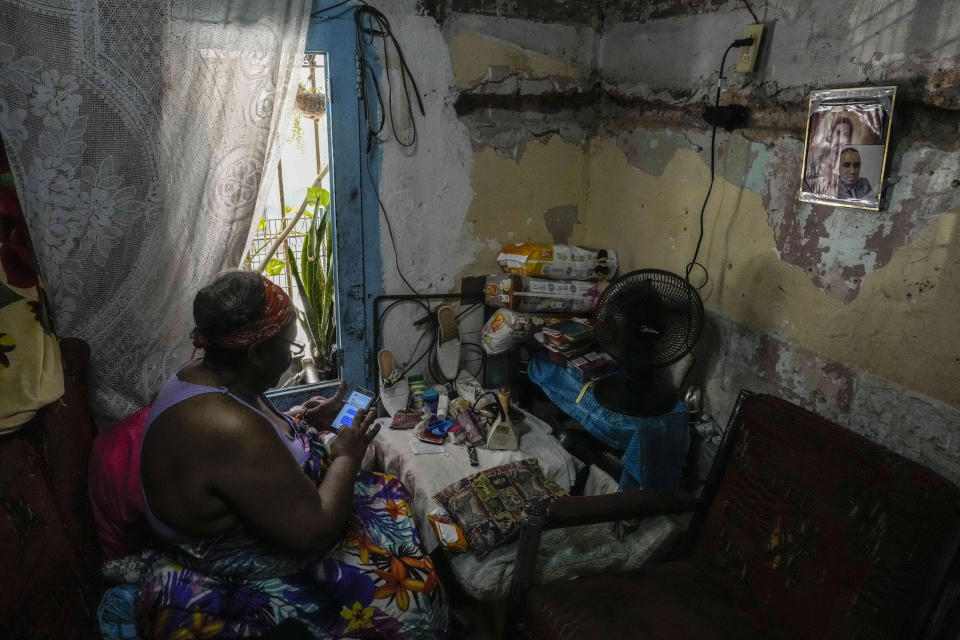 Olga Lidia Lahera sits in her home, a 15-square-meter (160-square-foot) apartment, where she lives with her daughter and two granddaughters in Havana, Cuba, Monday, June 13, 2022. Lahera, 65, was a state employee until she requested sick leave, and the four of them live off what the Cuban state give her daughter to take care of her and the girls. (AP Photo/Ramon Espinosa)