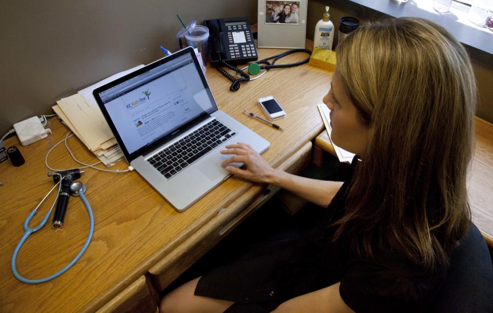 In this Friday, June 8, 2012 photo, Dr. Natasha Burgert works with patients while using social media as part of her practice, in Kansas City, Mo. There's a stereotype that says doctors shun technology that might threaten patients' privacy and their own pocketbooks. But a new breed of physicians is texting health messages to patients, tracking disease trends on Twitter, identifying medical problems on Facebook pages and communicating with patients through email. (AP Photo/Orlin Wagner)