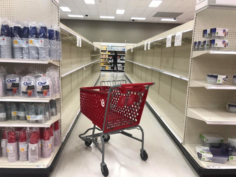 An abandoned shopping cart lies between empty paper towel aisles at a Target store in Culver City