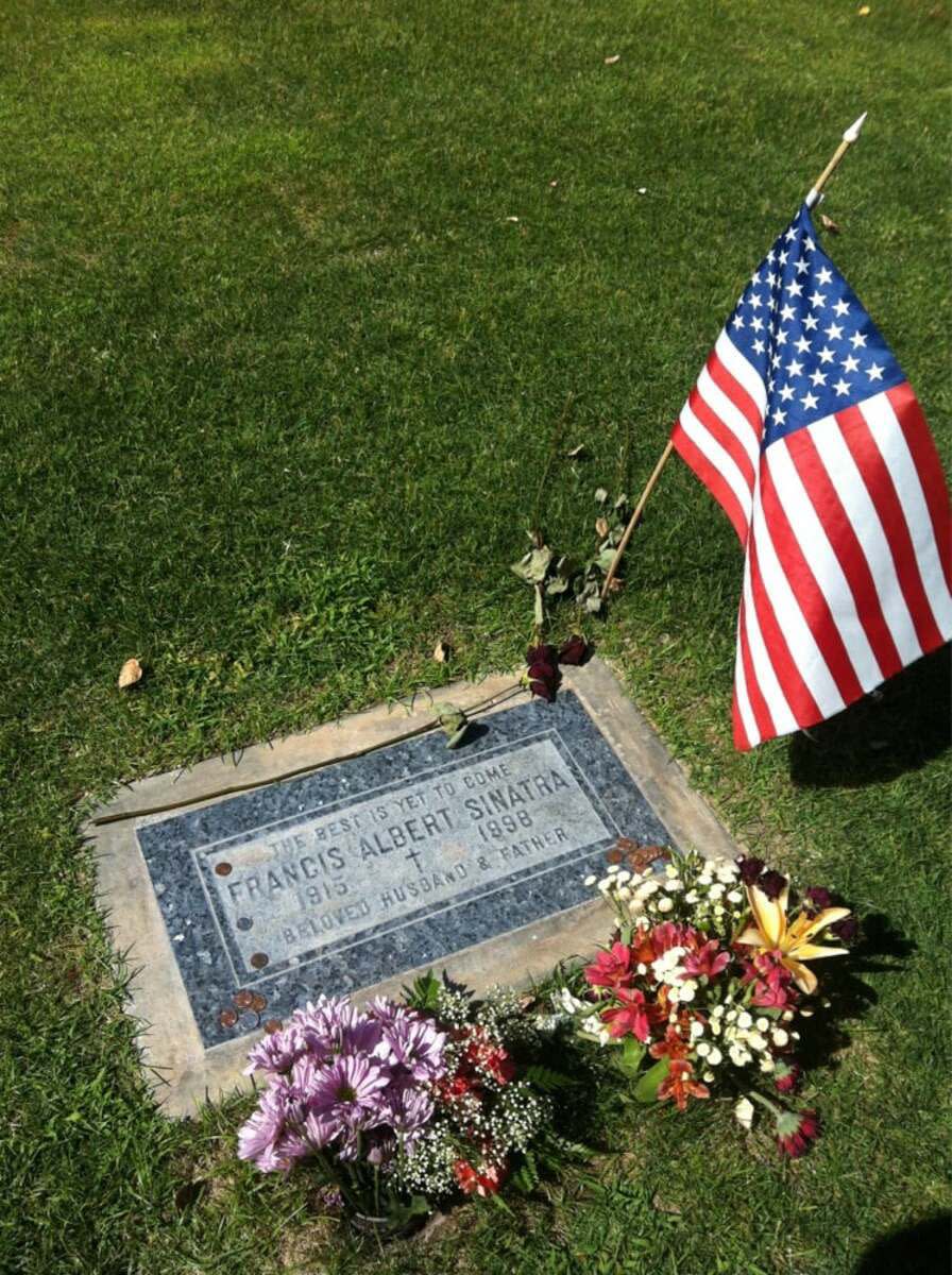 Frank Sinatra's grave in the Desert Memorial Park, Cathedral City, California with two batches of flowers and an American flag surrounded by grass