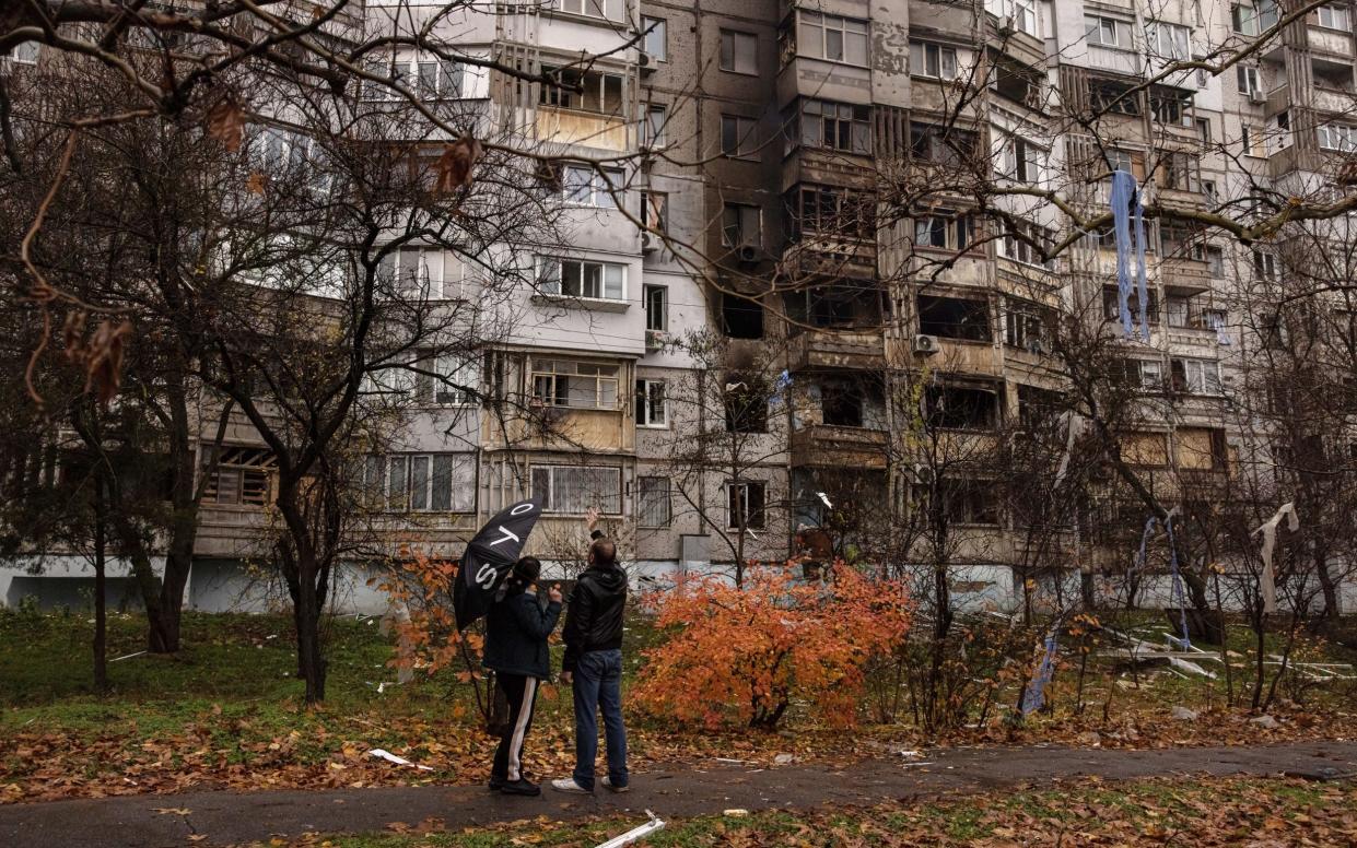 People look at a damaged residential building after the recent Russian attack, in Kherson