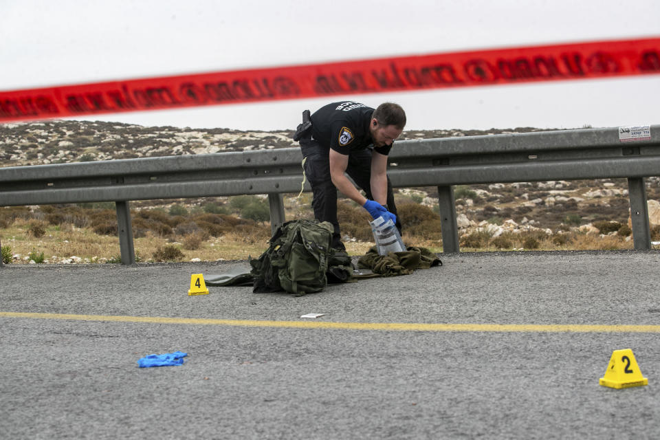 An Israeli police officer collects evidence after a Palestinian man rammed his car into an Israeli soldier, seriously injuring her, before he was shot dead by Israeli police near the Israeli settlement of Kochav Yakov, in the occupied West Bank, Tuesday, Nov. 29, 2022. He was the fourth Palestinian killed in a series of violent incidents on Tuesday. (AP Photo/Oren Ben Hakoon)