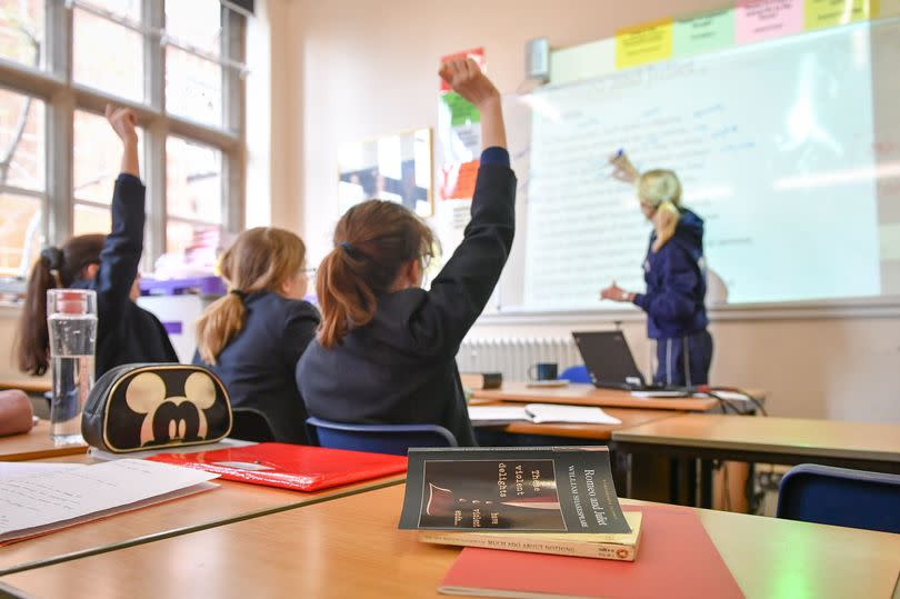 Children in a classroom with teacher writing on board