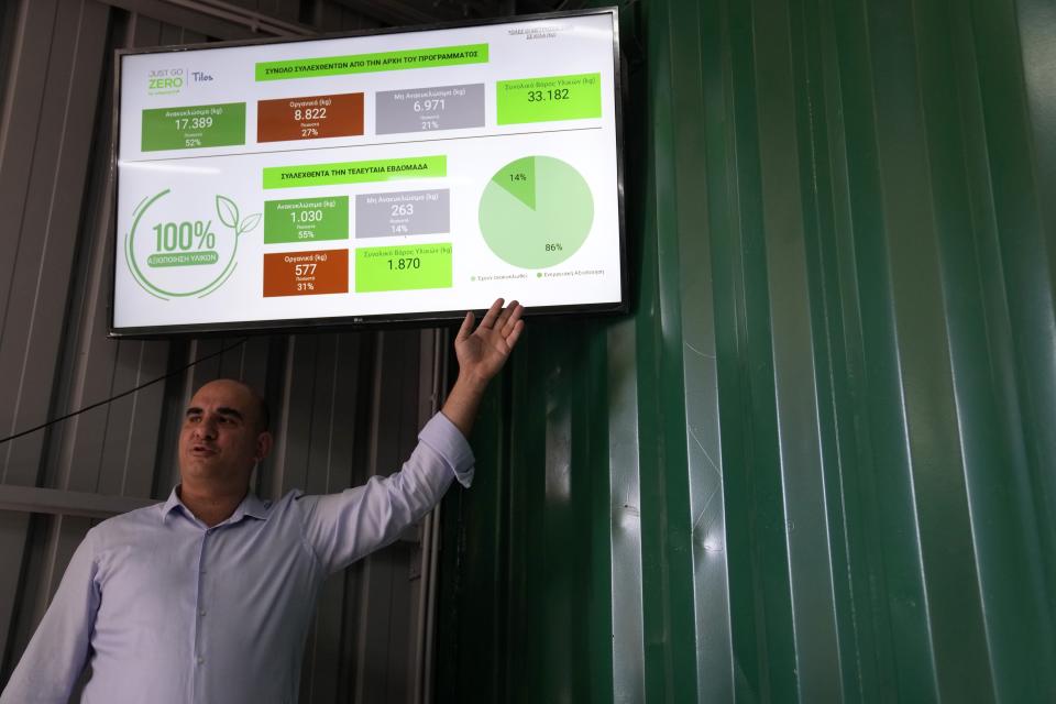 Founder and CEO of Polygreen recycling company Athanasios Polychronopoulos points toward a display showing data at a recycling plant built on old landfill site on the Aegean Sea island of Tilos, southeastern Greece, Monday, May 9, 2022. When deciding where to test green tech, Greek policymakers picked the remotest point on the map, tiny Tilos. Providing electricity and basic services, and even access by ferry is all a challenge for this island of just 500 year-round inhabitants. It's latest mission: Dealing with plastic. (AP Photo/Thanassis Stavrakis)