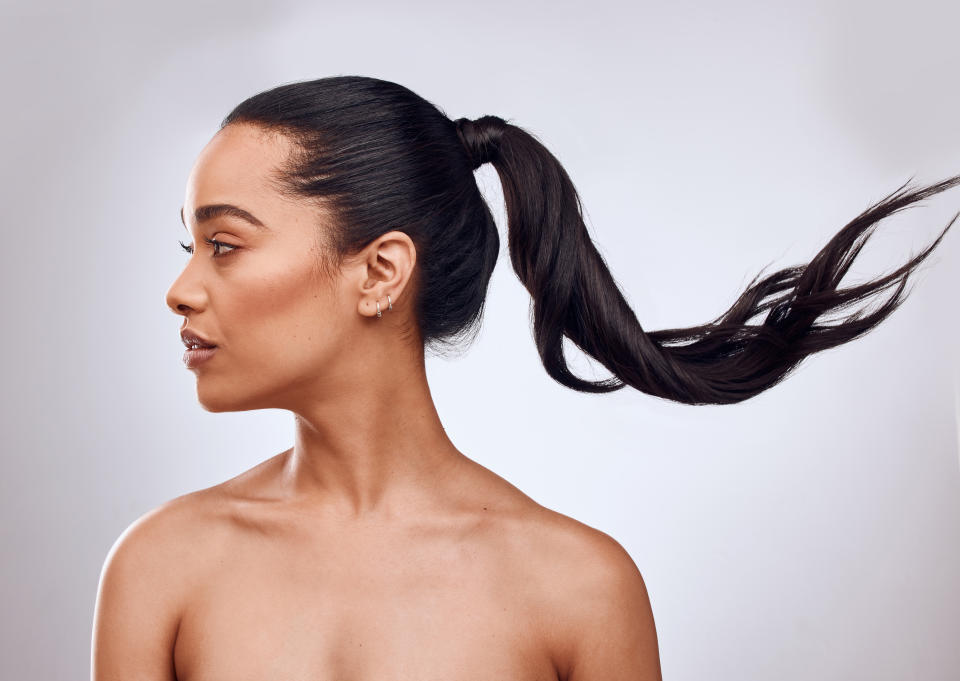 Beautiful black woman looking to her right with her long hair trailing off to the left from her ponytail.