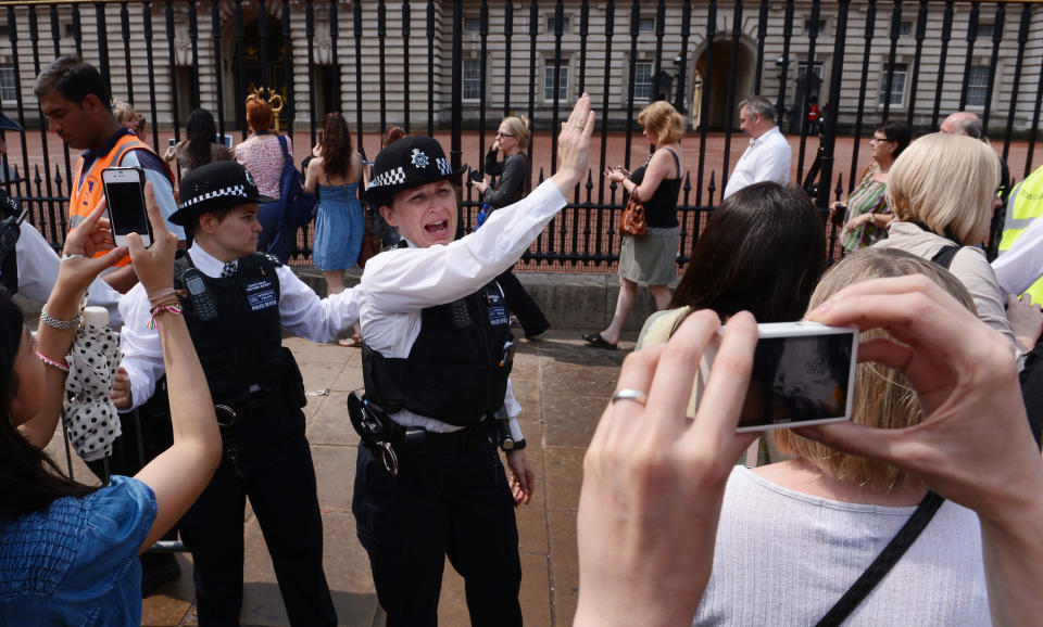 Police officers encourage members of the public, who are queuing to look at the official announcement that the Duke and Duchess of Cambridge have had a baby boy, to keep moving along, outside Buckingham Palace in London.