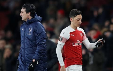 Mesut Ozil walks off behind Unai Emery - Credit: Reuters