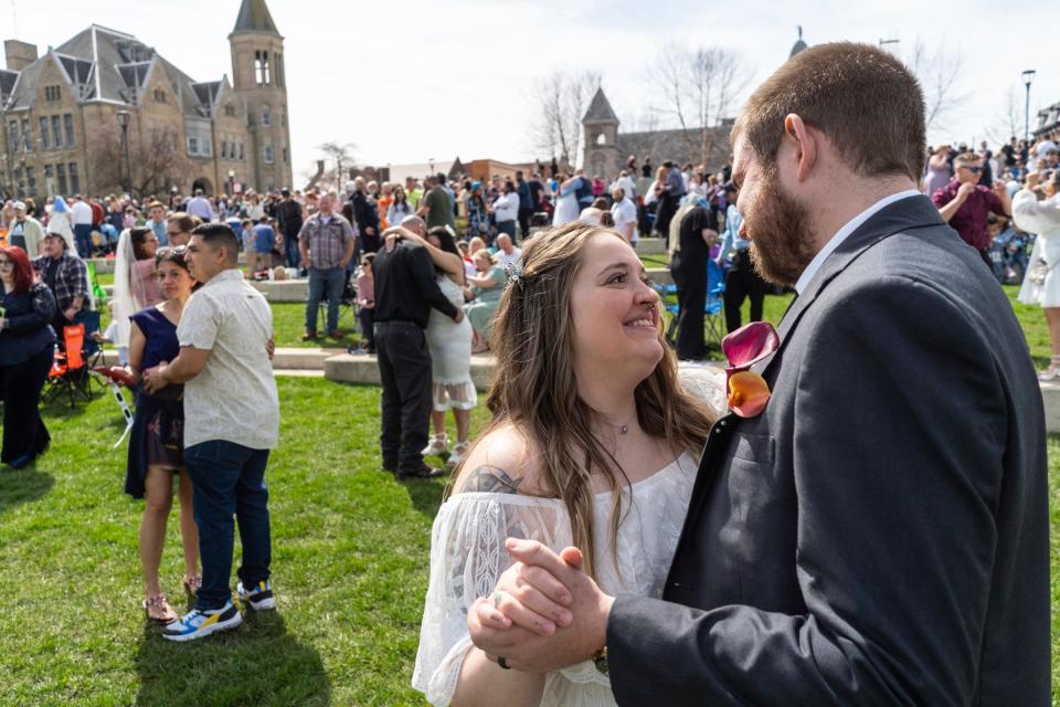 Jordan Golden, center, of Bowling Green, Ohio, dances with her husband Jack Golden for their first time together with other couples that were married during the Elope at the Eclipse event at the Frost Kalnow Amphitheater in Tiffin, Ohio on Monday, April 8, 2024. Over one hundred couples and their families gathered to be married or renew their vows during the totality of the eclipse event.