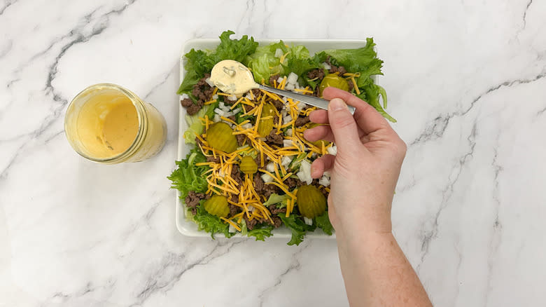 hand putting dressing on salad