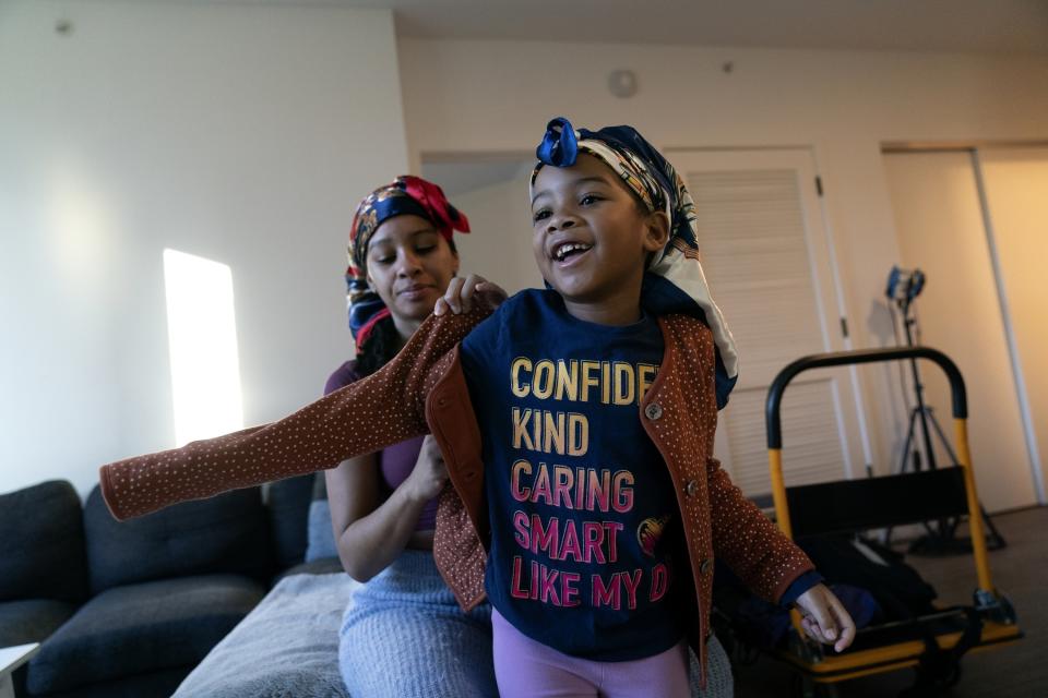 Johnae Strong helps her 6-year-old daughter Jari Akim with her coat as they ready for school and work Friday, Feb. 10, 2023, in Chicago. (AP Photo/Erin Hooley)