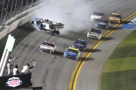 Denny Hamlin, front left, passes Ryan Blaney, front right on the way to the finish line to win NASCAR Daytona 500 auto race as Ryan Newman (6) goes upside down during a crash at Daytona International Speedway, Monday, Feb. 17, 2020, in Daytona Beach, Fla. Sunday's race was postponed because of rain. (AP Photo/David Graham)