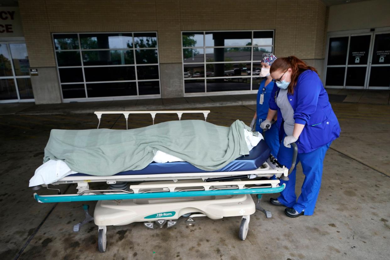 Medical staff prepare to move the body of a deceased COVID-19 patient to a funeral home van at the Willis-Knighton Medical Center in Shreveport, La., Wednesday, Aug. 18, 2021. 