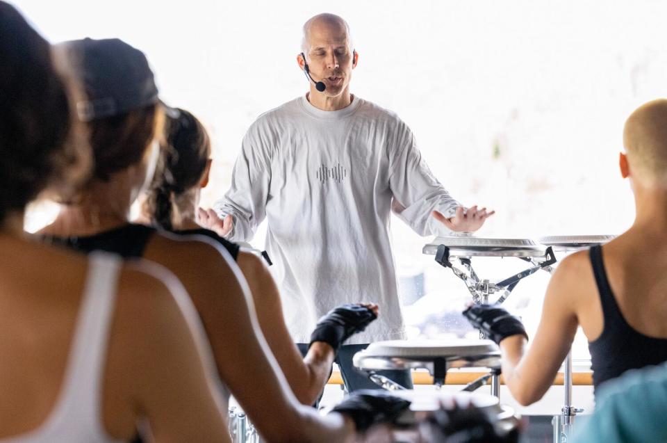 Drumboxing co-founder John Wakefield stands in front of the class, his hands hovering over conga heads on pedestals.