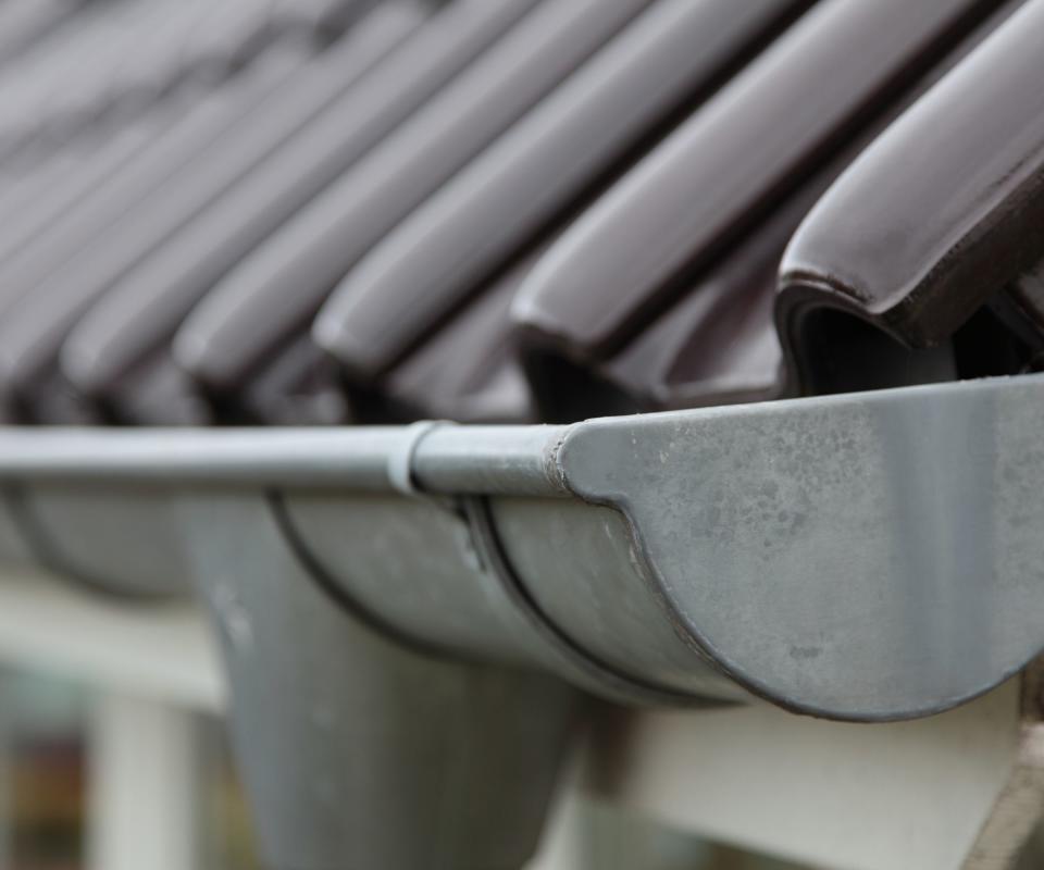 A gutter on roof full of leaves