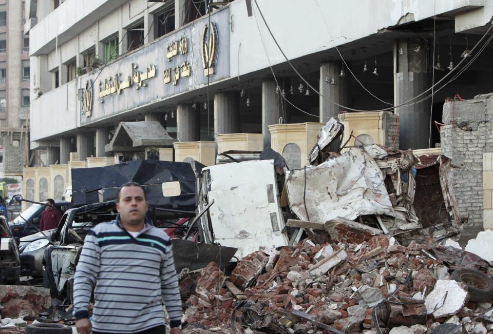 A man walks near debris after an explosion near a security building in Egypt's Nile Delta town of Dakahlyia