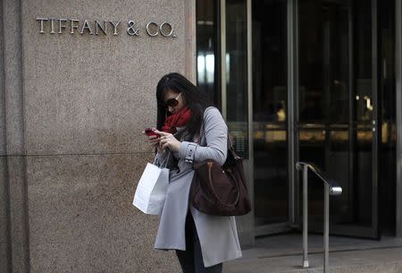 A visitor from China looks at her mobile phone after shopping at Tifany & Co. jewelers in New York City in this April 4, 2013 file photo. REUTERS/Mike Segar/Files