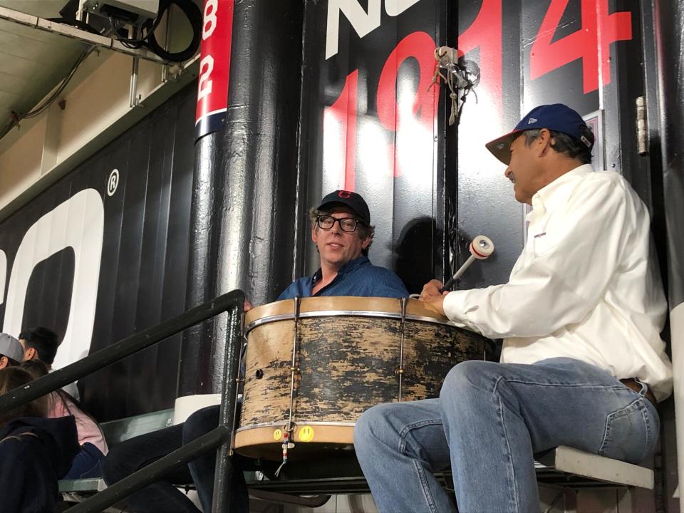 Black Keys drummer Patrick Carney (left) joined John Adams in the bleachers at a Cleveland baseball game in 2019 to beat the drums. Carney will fill in for Adams for the team's home opener on Monday.