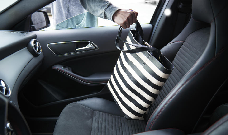 A hand can be seen reaching into an open car window to grab a black and white striped purse. A Montreal resident took to Reddit to ask what they should do after finding belongings stolen from their car for sale on Facebook Marketplace.