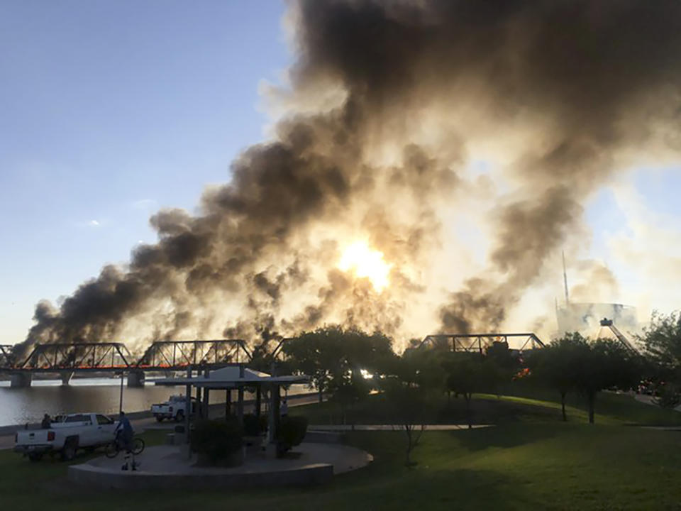 Smoke fills the sky at the scene of a train derailment in Tempe, Ariz., on Wednesday, July 29, 2020. Officials say a freight train traveling on a bridge that spans a lake in the Phoenix suburb derailed and set the bridge ablaze and partially collapsing the structure. There were no immediate reports of any leaks. (Daniel Coronado via AP)