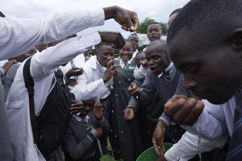 Students, many who are deaf or hard of hearing, from Chileshe Chepela Special School react as Bridget Chanda, center, signs for them during a climate smart technique lesson on drip irrigation outside a garden at the school in Kasama, Zambia, Wednesday, March 6, 2024. Chanda is intent on helping educate Zambia’s deaf community about climate change. As the southern African nation has suffered from more frequent extreme weather, including its current severe drought, it’s prompted the Zambian government to include more climate change education in its school curriculum. (AP Photo/Tsvangirayi Mukwazhi)