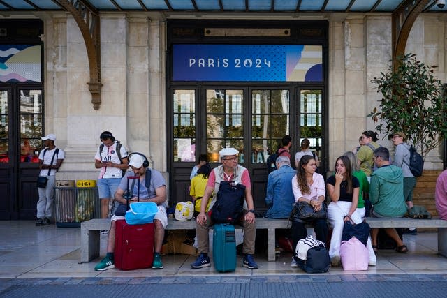 People with suitcases wait outside a French train station 