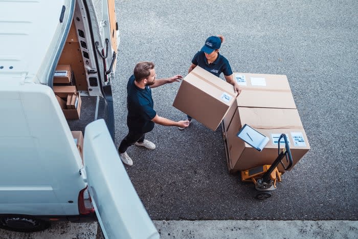 Two people loading up packages for delivery.