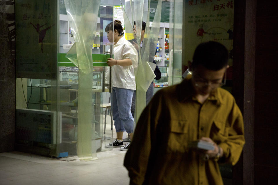 In this March 28, 2019, photo, people shop at a pharmacy that sold Tylox without a prescription in Xi'an in northwestern China's Shaanxi Province. Despite officially low numbers of prescription drug abuse, the Chinese government was worried enough about pain pill abuse that it pulled Tylox from most pharmacies in September. Officially, pain pill abuse is an American problem, not a Chinese one. But people in China have fallen into opioid addiction the same way many Americans did, through a doctor's prescription. And despite China's strict regulations, online trafficking networks, which facilitated the spread of opioids in the U.S., also exist in China. (AP Photo/Mark Schiefelbein)