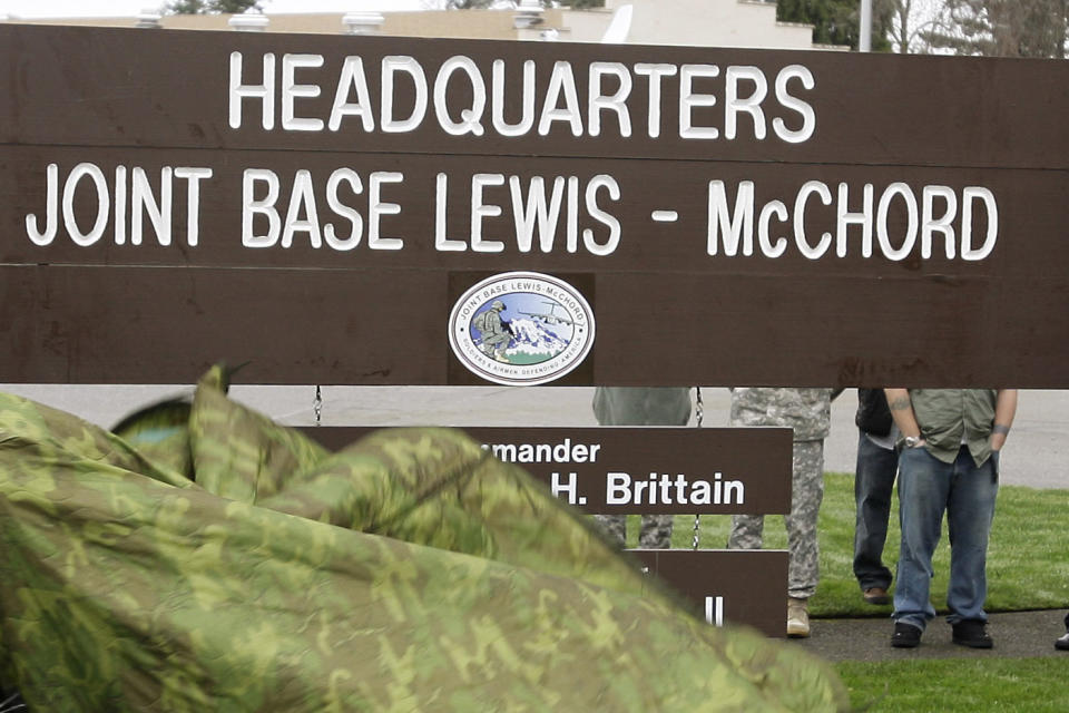 FILE - A new sign is unveiled during a ceremony marking the initial operational capability of the merger of Fort Lewis and McChord Air Force Base into Joint Base Lewis-McChord, Monday, Feb. 1, 2010, in Washington state. Fifteen current or retired Joint Base Lewis-McChord servicemen who say the Army failed to protect them from a military doctor who's been charged with sexual abuse are seeking $5 million in damages for the emotional distress they say they've suffered. (AP Photo/Ted S. Warren, File)