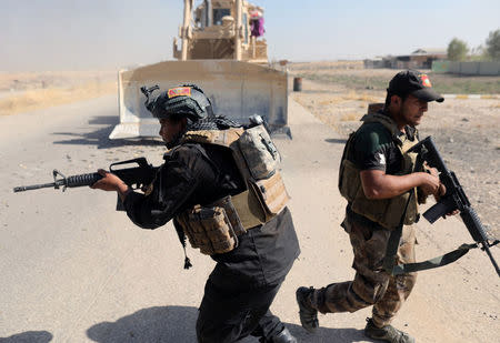 Iraqi special forces soldiers run for cover during clashes with Islamic States fighters in Bartella, east of Mosul. REUTERS/Goran Tomasevic