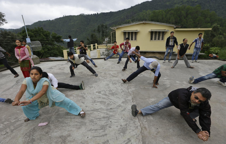 In this Aug. 25, 2012 photo, Dhiraj Dolwani, foreground right, CEO of B2R, exercises with employees at their center in Simayal, India. The three-year-old business is using the spread of the Internet to transport India's outsourcing boom from metropolitan areas to this farming village in the Himalayan foothills. B2R and a handful of similar firms are trying to offer an alternative road map for Indian economic growth. With nearly 70 percent of the population - 833 million people - living in rural areas and its cities already overburdened, there is a limit to how quickly the nation can urbanize. (AP Photo/Saurabh Das)