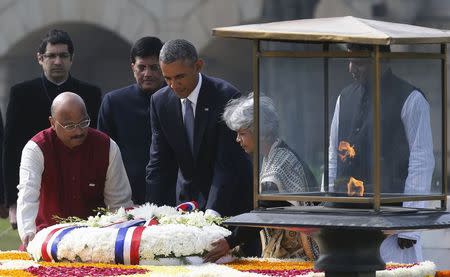 U.S. President Barack Obama (C) lays a wreath next to the eternal flame at the Raj Ghat Mahatma Ghandi memorial in New Delhi January 25, 2015. REUTERS/Jim Bourg