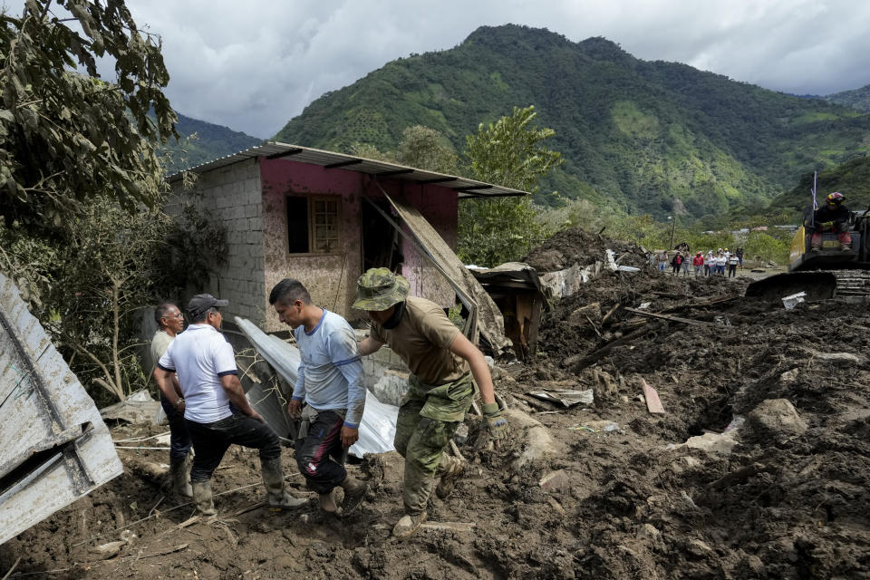 A resident, second from right, reacts after landslides damaged his house in El Placer, Ecuador, Monday, June 17, 2024. (AP Photo/Dolores Ochoa)