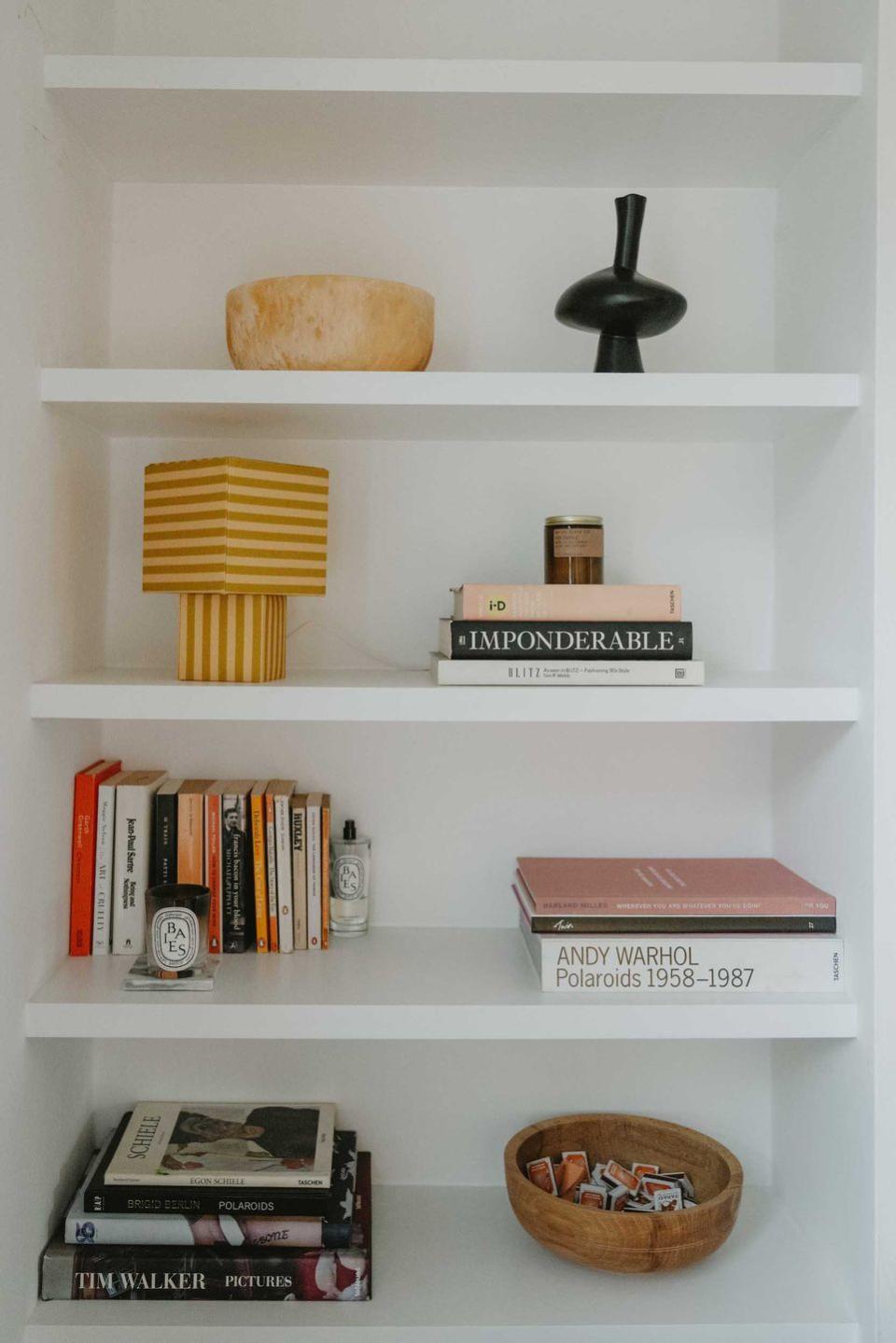 a white shelving unit with books and a basket