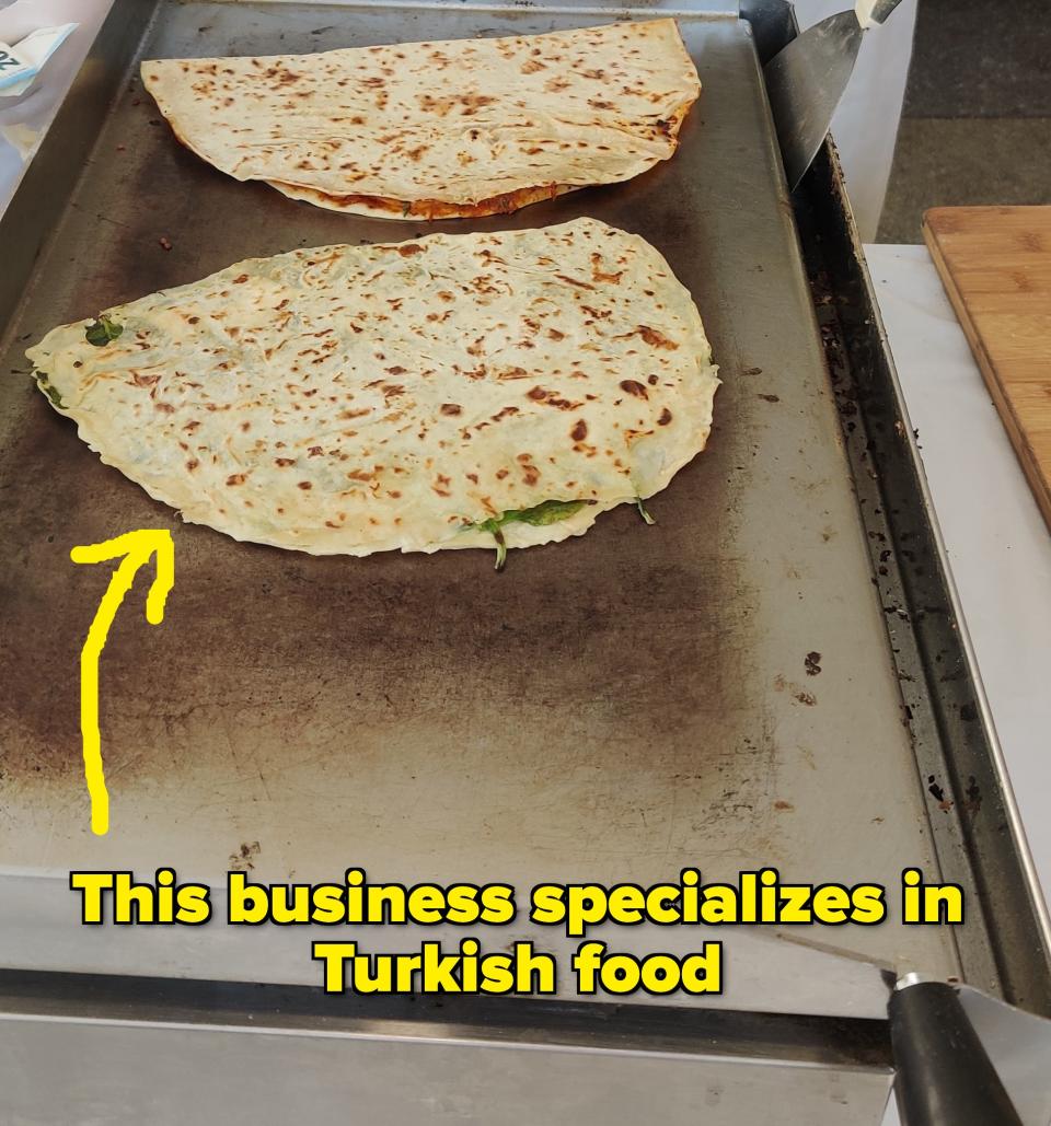 Chefs preparing traditional flatbreads on a hot griddle at a street market