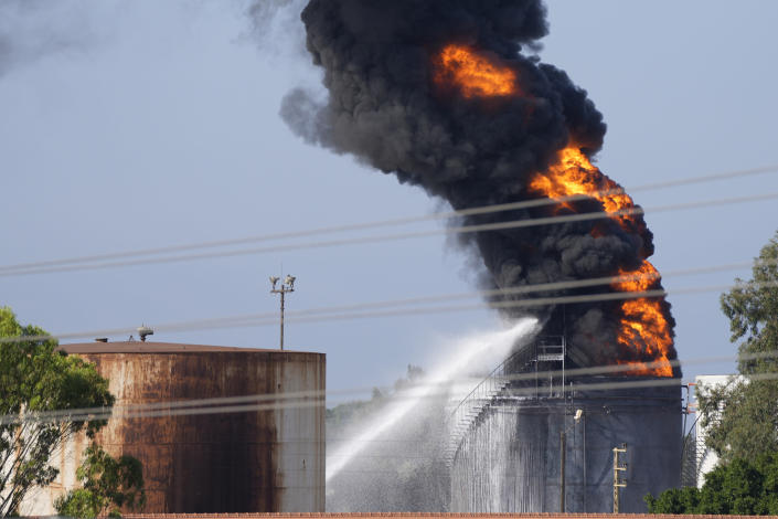 Firefighters work to extinguish a fire in an oil facility in the southern town of Zahrani, south of the port city of Sidon, Lebanon, Monday, Oct. 11, 2021. A huge fire broke out at an oil facility in southern Lebanon's coastal town of Zahrani, but the cause was not immediately known. (AP Photo/Hassan Ammar)