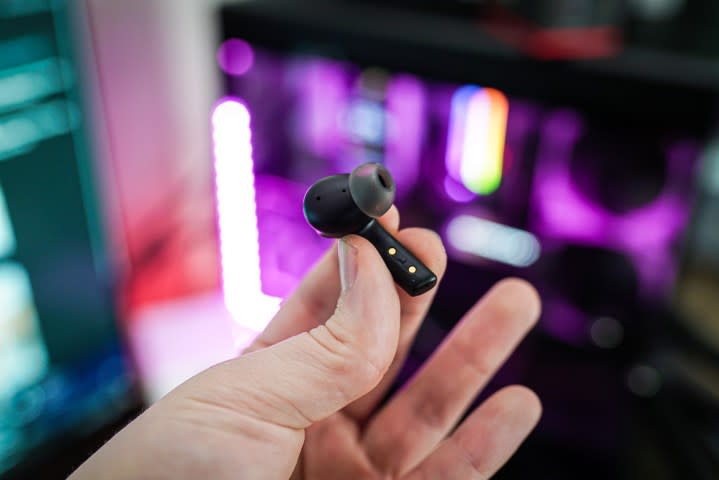 A hand holding the left side of the Asus Cetra Speednova earbuds. 