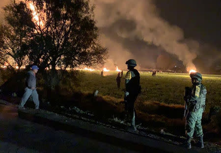 Military personnel watch as flames engulf an area after a ruptured fuel pipeline exploded, in the municipality of Tlahuelilpan, Hidalgo, Mexico, near the Tula refinery of state oil firm Petroleos Mexicanos (Pemex), January 18, 2019 in this handout photo provided by the National Defence Secretary (SEDENA). National Defence Secretary/Handout via REUTERS