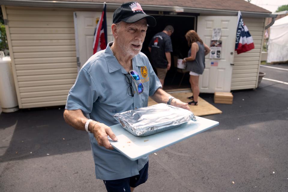 (Left) Forrest Elliott carries a tray of food as he volunteers at American Legion Post 310 in Little Ferry during their annual pig roast to raise money for veterans on Saturday, July 15, 2023. Elliott, a retired middle school teacher, has devoted his life to helping others.