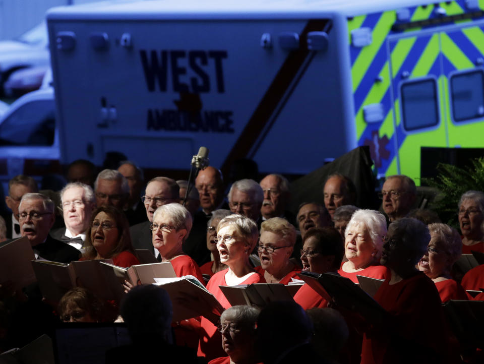 A West emergency vehicle sits parked behind the Baylor Singing Seniors, a choir, as they perform at the beginning of a memorial service, Thursday, April 17, 2014, in West, Texas, honoring the persons who were killed in a fertilizer plant explosion one year ago. (AP Photo/Tony Gutierrez)