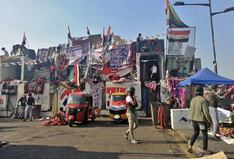 Anti-government protesters sit-in on barriers set up by security forces to close a bridge leading to the Green Zone government areas during ongoing protests, in Baghdad, Iraq, Monday, Nov. 11, 2019. (AP Photo/Khalid Mohammed)