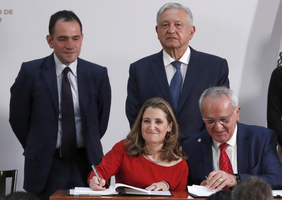 FILE - In this Dec. 10. 2019 file photo, Mexico's Treasury Secretary Arturo Herrera, left, standing next to Mexico's President Andres Manuel Lopez Obrador, attend a trade agreement signing ceremony at the National Palace in Mexico City. Herrera reported on Thursday, June 25, 2020 that he has contracted the new coronavirus. (AP Photo/Marco Ugarte, File)