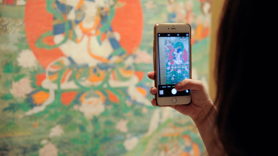 A guest takes a photo of Buddhist artwork during the 2016 Asia Week Celebration at Rubin Museum of Art on March 17, 2016. - Matthew Eisman/Getty Images