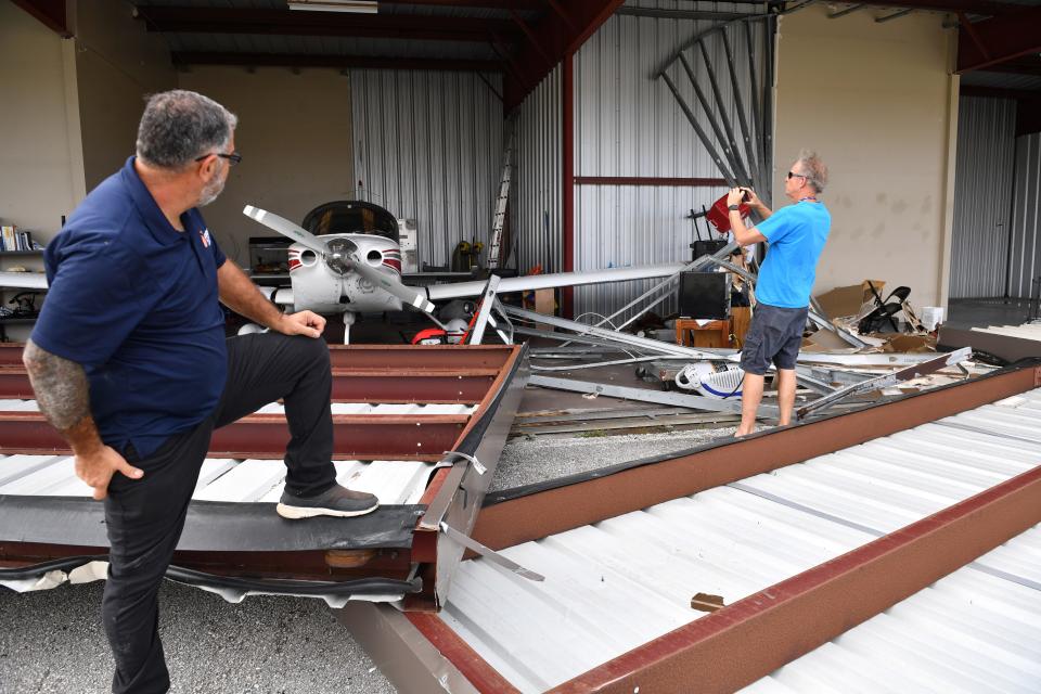 Andre Ghawi, left, watches at Dennis King take a photo of his Grumman Cheetah in a hanger at the Venice Municipal Airport following Hurricane Ian on Thursday, Sept. 29, 2022 in Venice, Florida..  Ghawi lost two aircraft in the storm. "They were in the hanger.  The hanger doesn't exist anymore" he said. King's aircraft fared better with damage to the prop and right wing.   