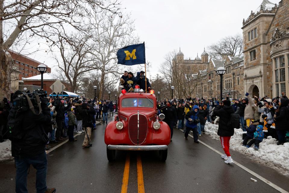 An old fire truck carrying Michigan head football coach Jim Harbaugh and some of his star players heads down South University Avenue toward South State Street as Michigan fans yell and cheer on both sides of the street as they celebrate the newly crowned national champions during the parade on campus in Ann Arbor on Saturday, Jan. 13, 2024.