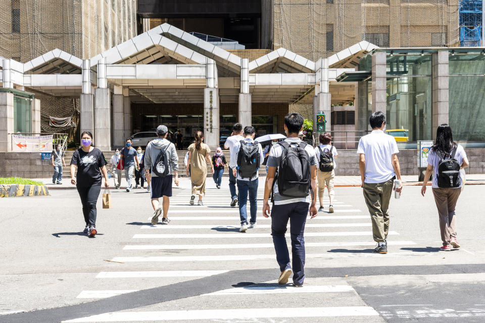 Taipei, Taiwan- August 26, 2021: Pedestrians cross the road at the intersection in front of National Taiwan University Hospital. People wear a mask to protect themselves during the COVID-19 outbreak.