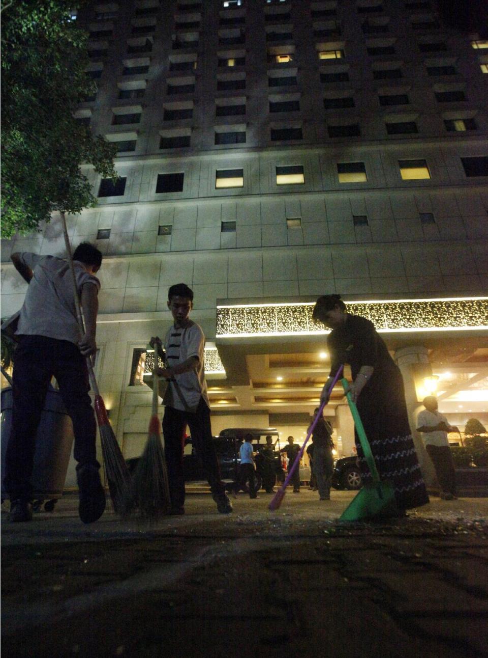 Staff clean up outside the Traders Hotel in Yangon, Myanmar Tuesday, Oct 15, 2013 following an explosion just before midnight Monday, which ripped apart a guest's 9th floor bathroom and slightly wounded an American woman in the latest in a series of unexplained blasts to hit the Southeast Asian country. It was not immediately clear what caused the explosion but the incident came after unidentified assailants planted three homemade bombs in and around Yangon in recent days, reportedly killing two people and injuring three others. (AP Photo/Khin Maung Win)