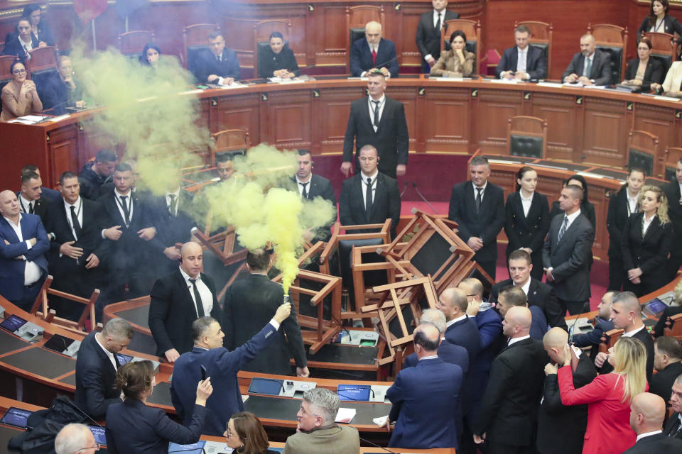 Asllan Gogjani, Democratic lawmaker, holds flares during a parliament session in Tirana, Albania, Thursday Dec. 7, 2023. The Albanian Parliament on Thursday passed the annual budget and other draft laws in a disrupted vote from the opposition using flares and noise to protest against what they consider as an authoritarian rule from the governing Socialist Party. (AP Photo/Armando Babani)