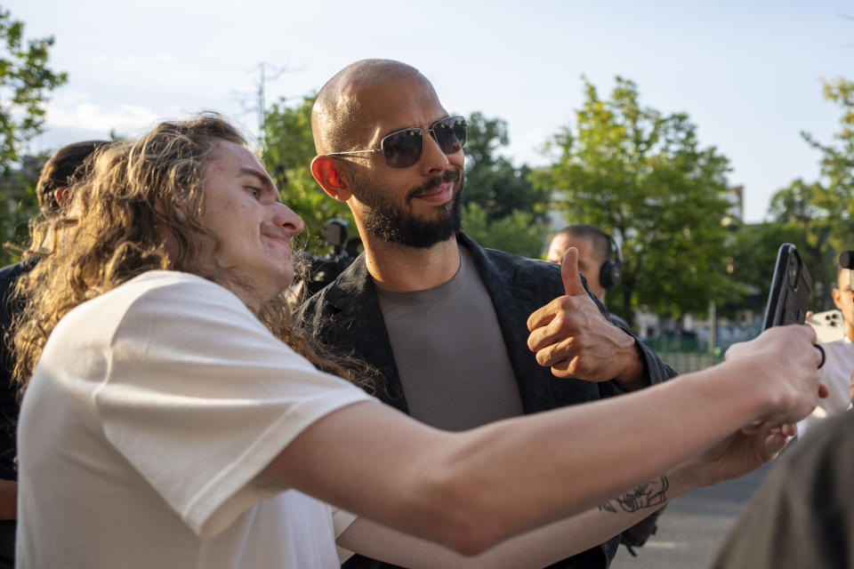 Andrew Tate gives a thumbs up while posing with a fan upon exiting the Court of Appeal in Bucharest, Romania, Thursday, July 6, 2023. Andrew Tate, the divisive social media personality and former professional kickboxer who is charged in Romania with rape, human trafficking, and forming a criminal gang to sexually exploit women, lost an appeal on Thursday against a court's earlier decision to keep him under house arrest, his spokesperson said. (AP Photo/Andreea Alexandru)