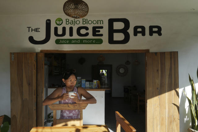 Suti Ana holds a coffee as she waits for costumers at her cafe shop in Labuan Bajo, East Nusa Tenggara province, Indonesia, Monday, May 8, 2023. Indonesian President Joko Widodo will host fellow leaders of the Association of Southeast Asian Nations this week in their annual summit in Labuan Bajo. (AP Photo/Achmad Ibrahim)